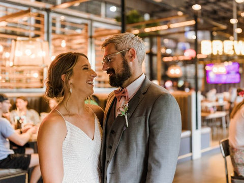 Couple in wedding attire standing close together in a restaurant setting.