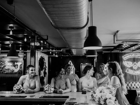 Group of women sitting at a bar with floral arrangements, in a casual setting.